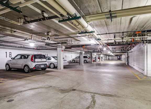 A parking garage with two cars parked in it.