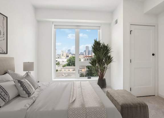 A bedroom with a large bed and a view of the city.