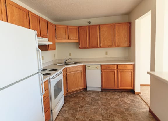 A kitchen with brown cabinets and white appliances.
