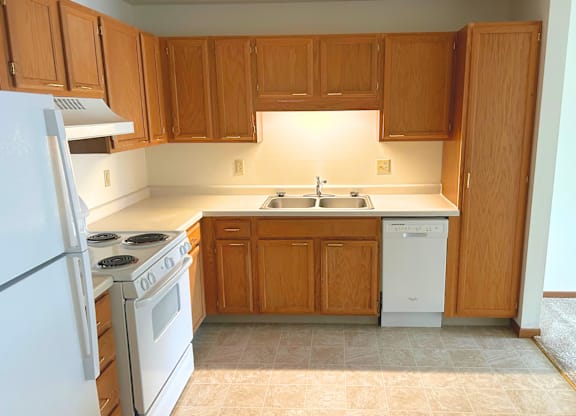 A kitchen with wooden cabinets and a white dishwasher.