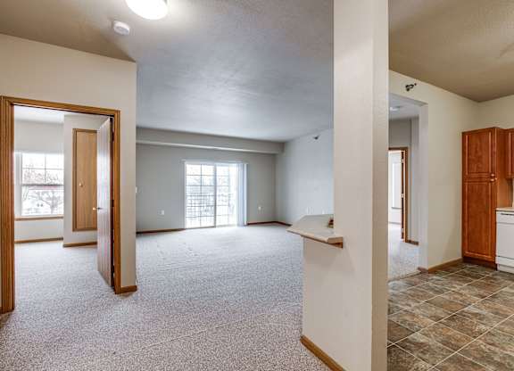 A large, empty room with a kitchen area to the right.