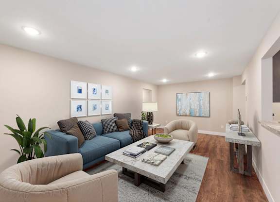 A living room with a blue couch, a grey coffee table, and a white chair.