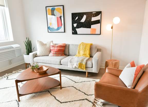 A living room with a white couch, a brown armchair, and a wooden coffee table.