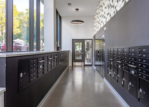 a long hallway with rows of mailboxes in a building with large windows