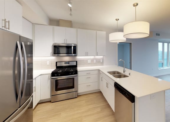 a white kitchen with stainless steel appliances and white counter tops