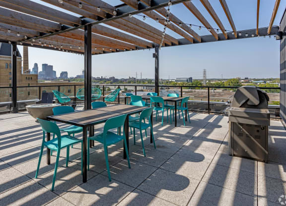 a roof deck with tables and chairs and a city in the background