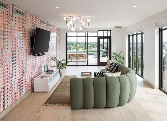 A living room with a green couch and a television on the wall.