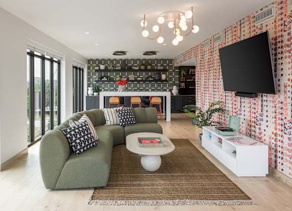 A modern living room with a green sofa and a patterned wallpaper.