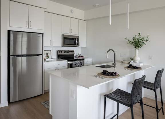 A kitchen with a white counter and a black chair.