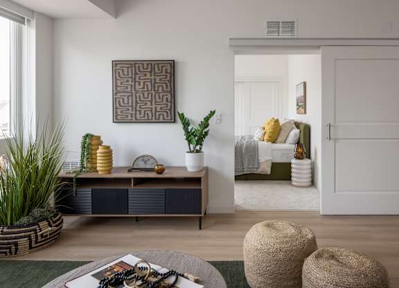 A living room with a brown and white cabinet, a green rug, and a large abstract painting on the wall.