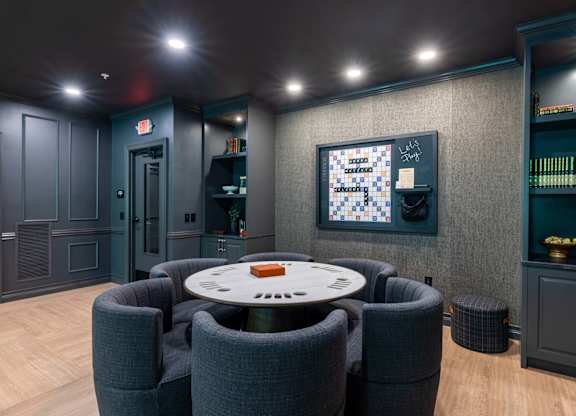 A room with a round table surrounded by grey chairs.