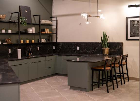 A kitchen with a black countertop and grey cabinets.