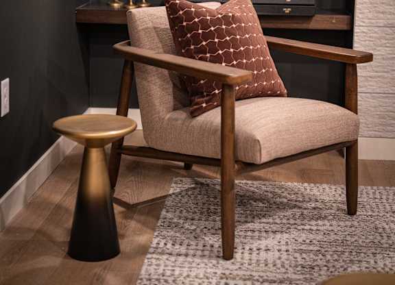 A chair with a pillow and a small table in front of a shelf.