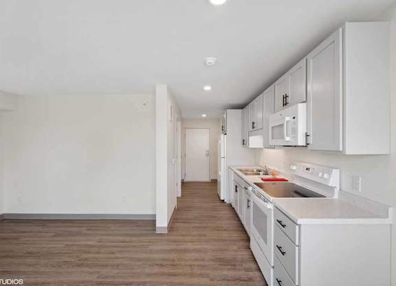 a white kitchen with white cabinets and white appliances and a wooden floor