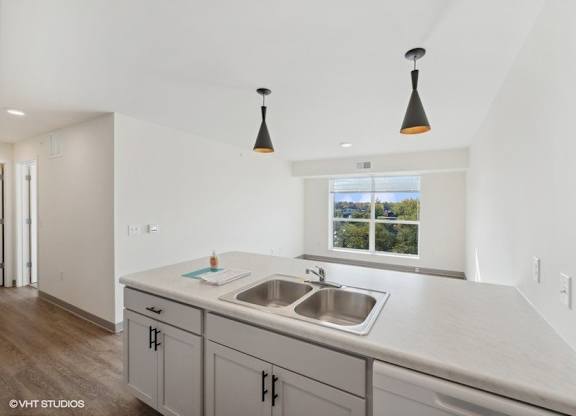 a kitchen with white cabinets and a sink and a window