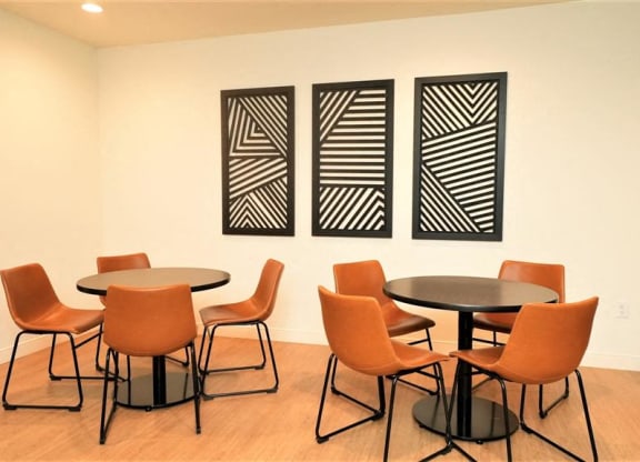 a room with tables and chairs and three paintings on the wall
