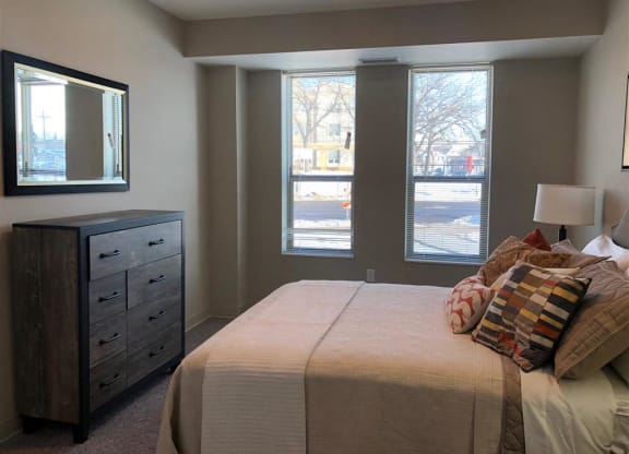 a bedroom with a bed and a dresser and three windows