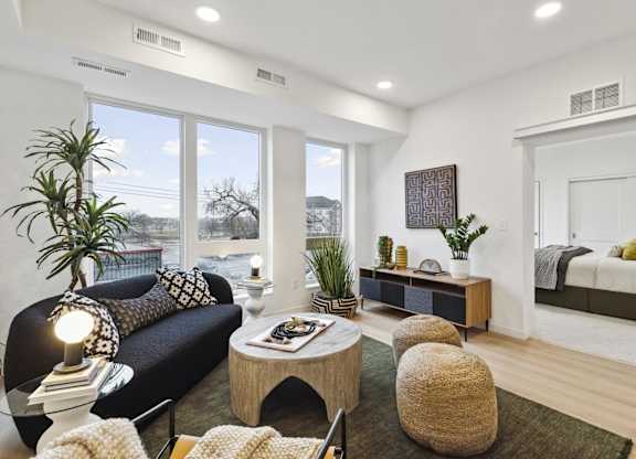 A living room with a black couch, a coffee table, and a large window.