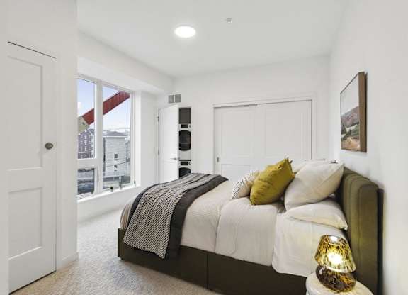 A bedroom with a bed, pillows, and a lamp.