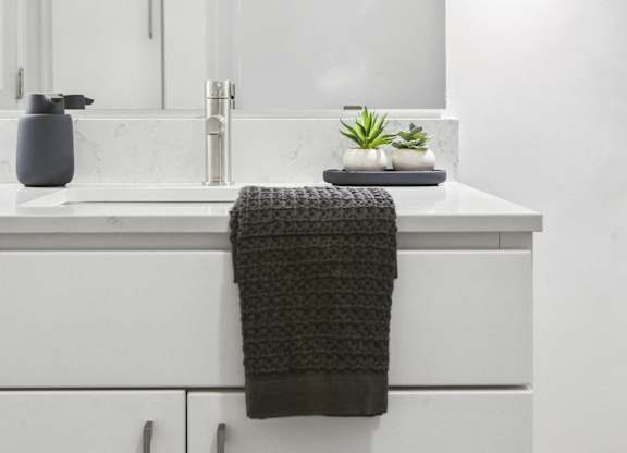 A bathroom with a white counter and a grey towel.