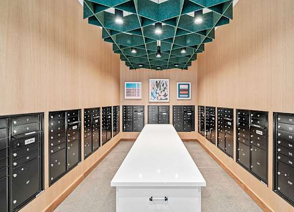 A long white table is in the middle of a room with black filing cabinets on both sides.