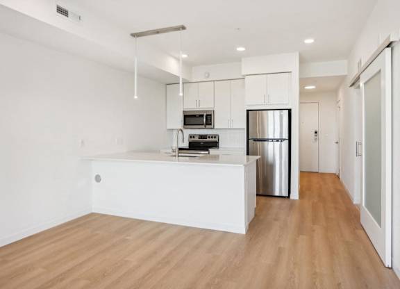 A kitchen with stainless steel appliances and wooden floors.