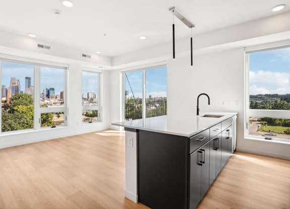 A kitchen with a black counter and cabinets with a view of the city.
