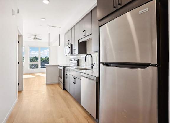 A modern kitchen with stainless steel appliances and wooden floors.