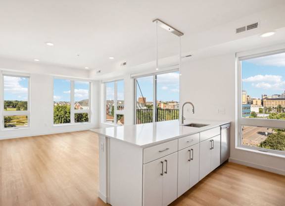 A kitchen with white cabinets and a large window overlooking a cityscape.