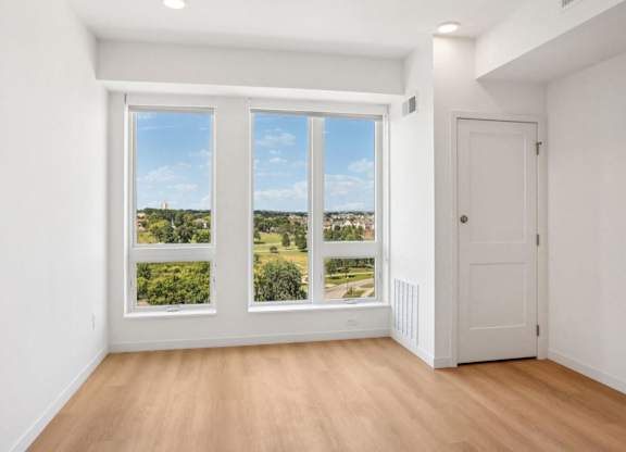 A room with a large window overlooking a green landscape.