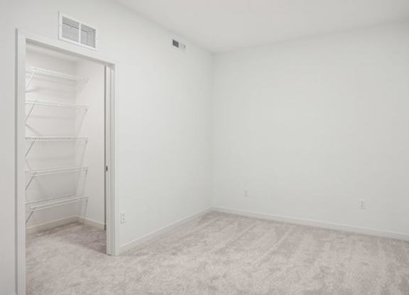A white room with a door and a shelf.