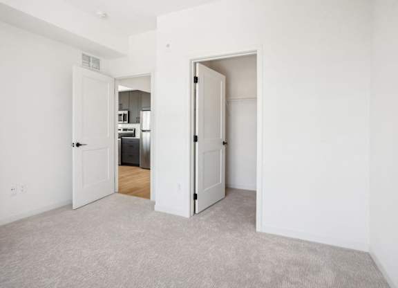 A white room with a carpeted floor and two open doors.