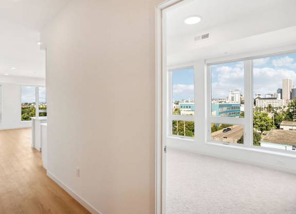 A white room with a view of the city through the windows.