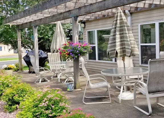 A patio with a table and chairs under a wooden pergola.