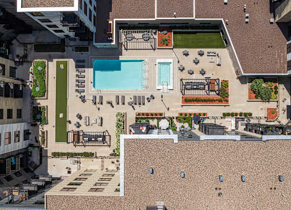 A rooftop patio with a pool and a table with chairs.