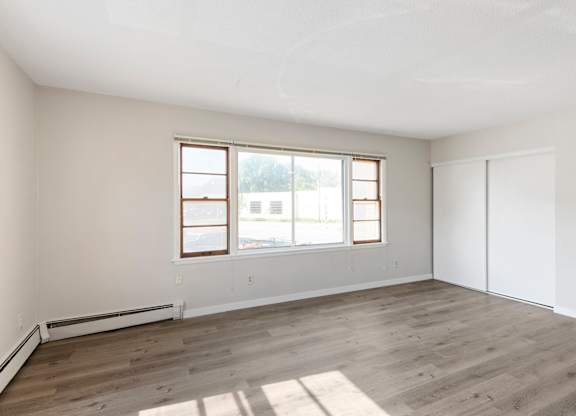 A room with a window and a wooden floor.