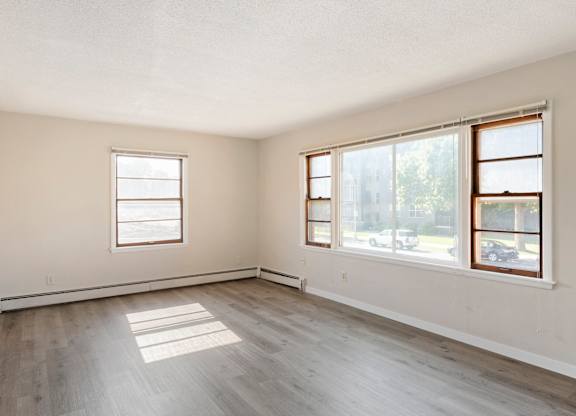 A room with two windows and wooden flooring.
