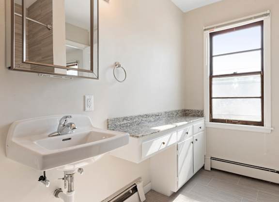 A bathroom with a sink, mirror, and window.