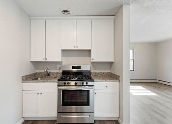 A kitchen with white cabinets and a granite countertop.