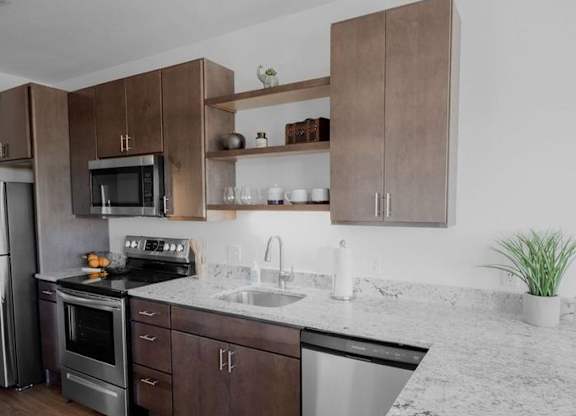 A kitchen with brown cabinets and a marble countertop.