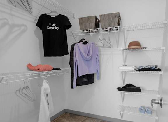 A white closet with a black shirt that says "Hello Saturday" hanging on the wall.