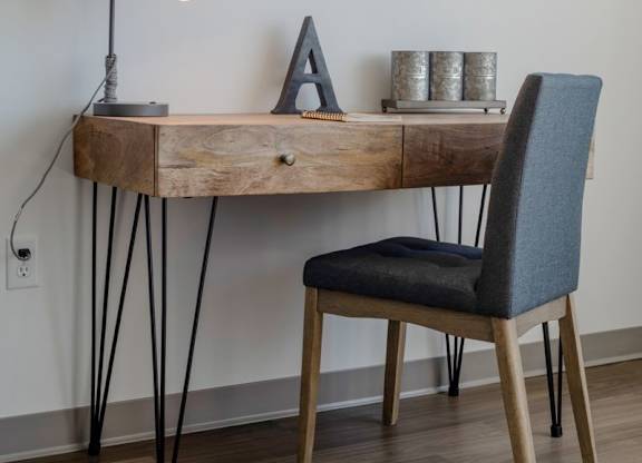 A wooden desk with a chair and a lamp on it.