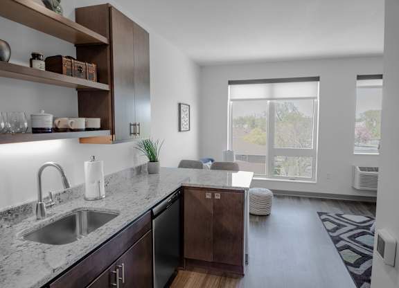 A modern kitchen with dark wood cabinets and a marble countertop.