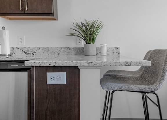 A kitchen counter with a chair and a plant on it.