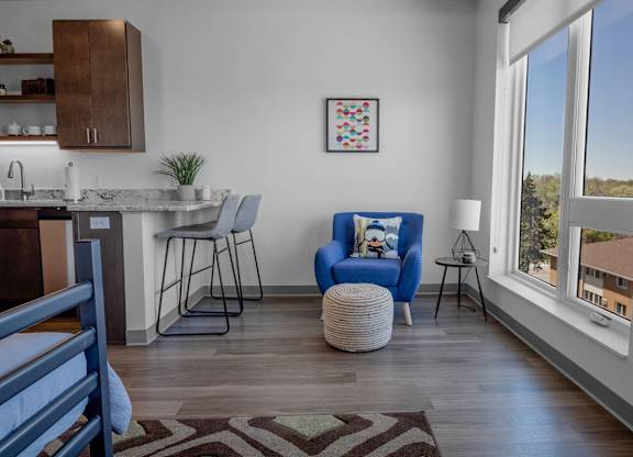 A blue chair with a pillow and a small table in front of a window.