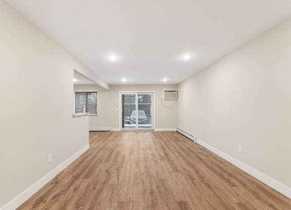 A long, empty room with wooden floors and white walls.