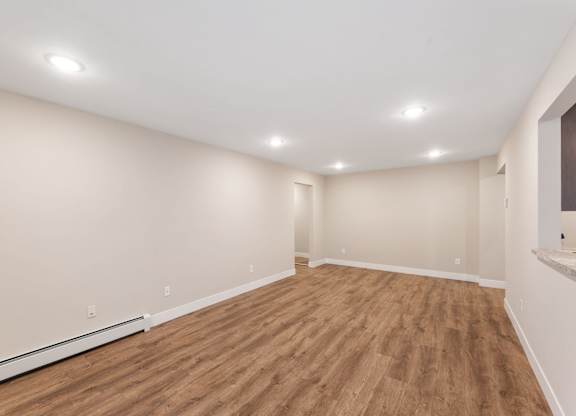 Empty room with wooden flooring and white walls.