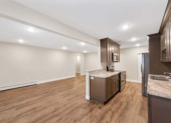 A kitchen with a wooden floor and a stainless steel refrigerator.
