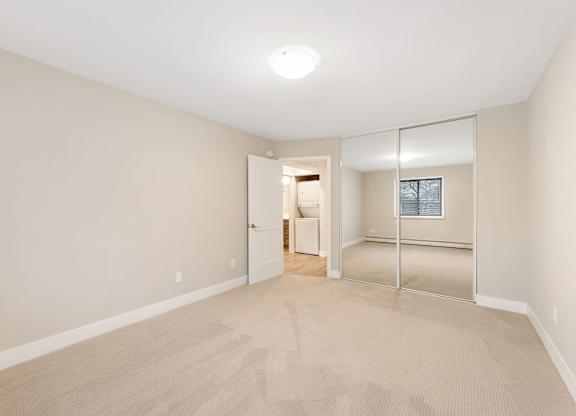 A room with a carpeted floor and a mirrored doorway leading to another room.