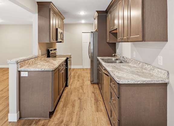 A kitchen with brown cabinets and a marble countertop.